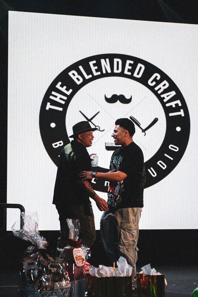 Two men on stage with The Blended Craft Barber Studio logo backdrop