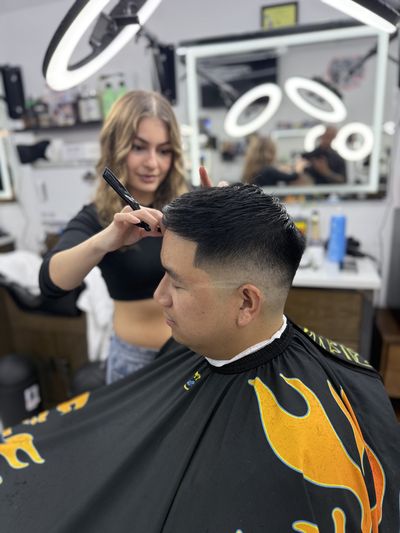 Barber detailing a crisp fade on a client in a flame cape